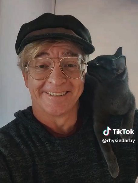 Rhys Darby with a grey kitten on his shoulder