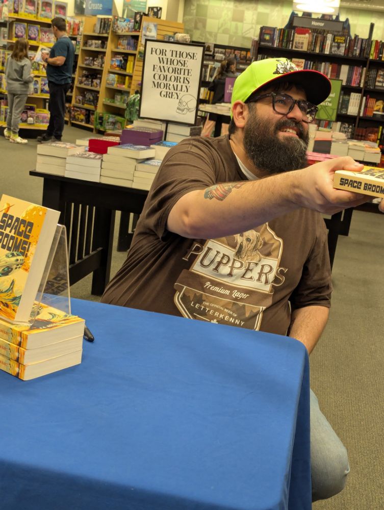 Handing over a signed copy of Space Brooms! to a guest.