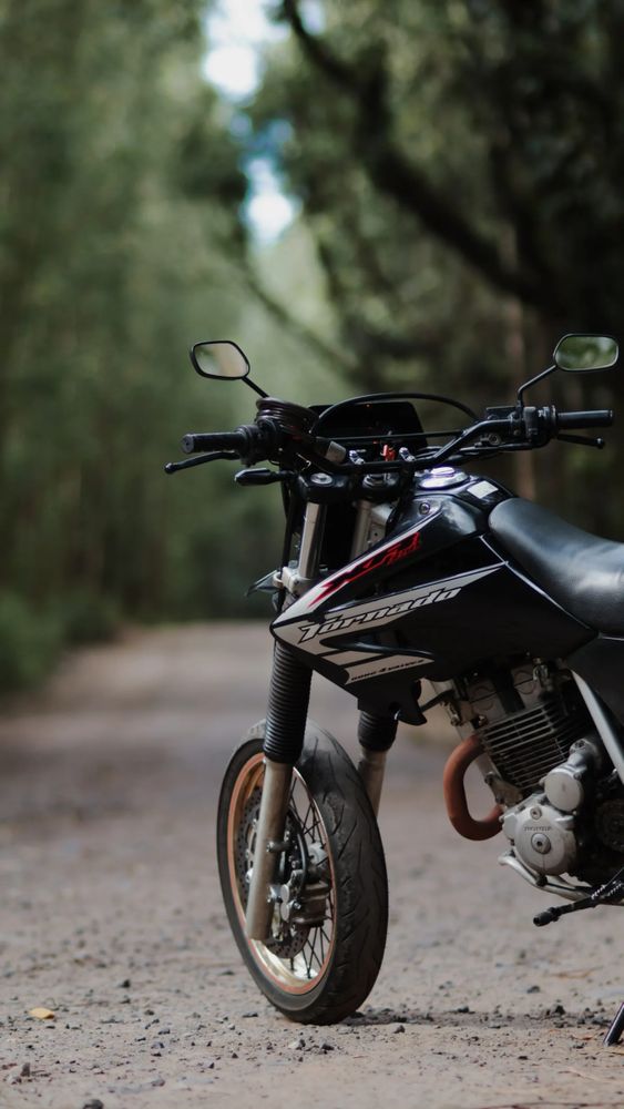 a black xr250 motorcycle in front of a path through big trees 