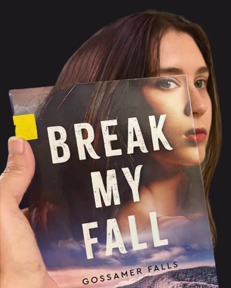 Bookface photo of staff member with the book “Break My Fall” by Lynn Huggins Blackburn. Bookface photos are when staff pose with a book cover to visually align themselves with the image on the cover, creating an optical illusion.  
