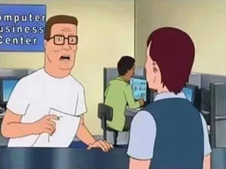 Hank Hill holding piece of paper looking annoyed talking to employee at Computer Business Center 