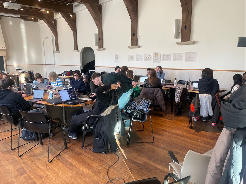 Room full of people working on laptops in a beautiful medieval room