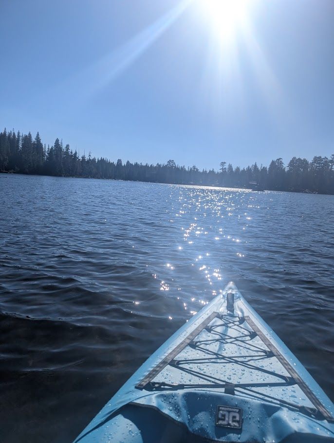 Photo of sun sparkling off the water in front of a kayak, which was probably taken moments after my kid's phone fell into that lake...
