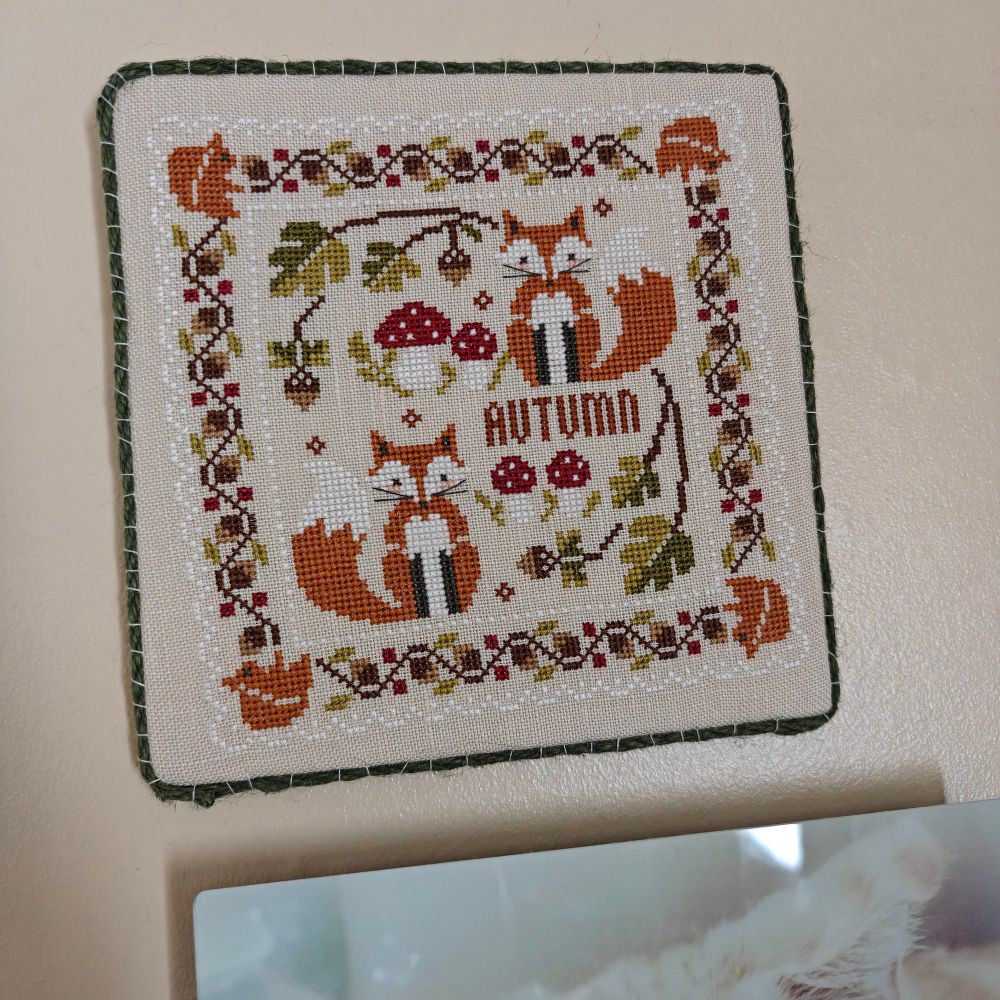 The Two Foxes mini cross stitch sampler hanging on the wall