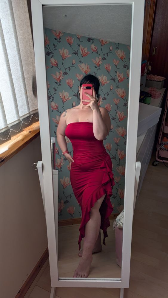 Photo of myself in a deep red mid length dress, strapless with a slit at the thigh with ruffles along the inner part of the slit 