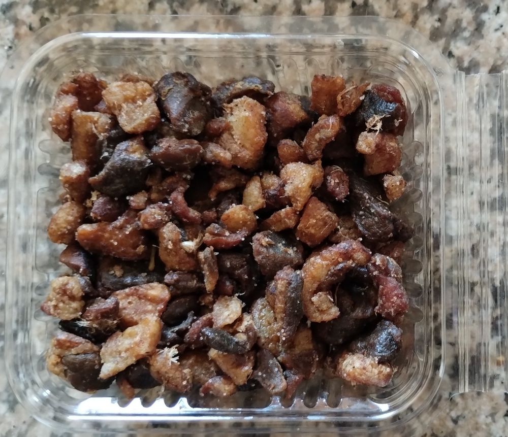 Photo de dessus d'une boîte de grattons. 
D'après wikipédia : "Les grattons (parfois gratons, très rarement au singulier) sont des aliments composés de tissus adipeux de porc, d'oie, de poulet ou de canard, confits dans leur graisse."