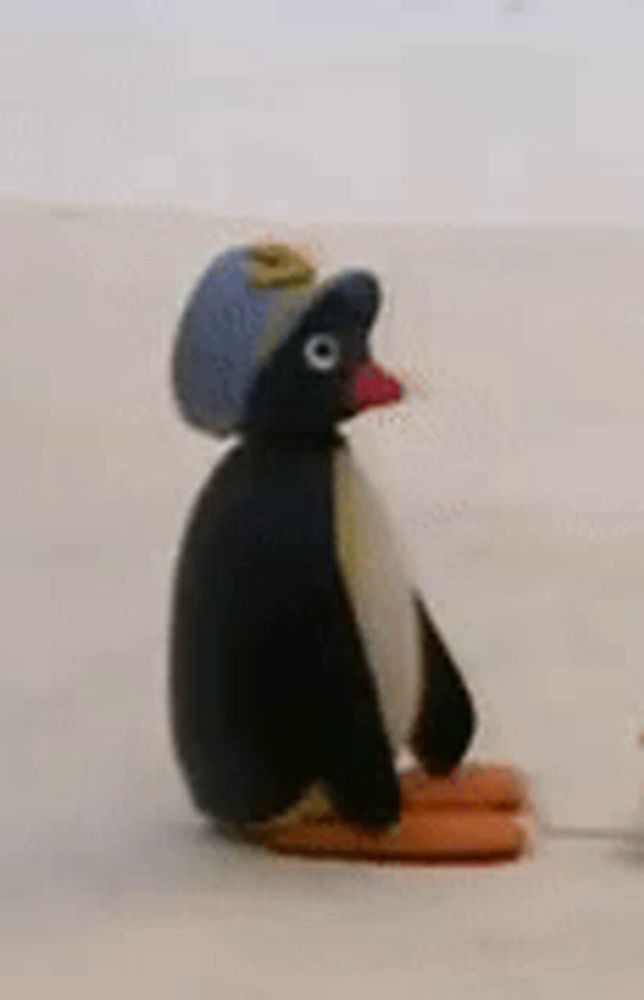 a stuffed penguin wearing a hat is sitting on a table .