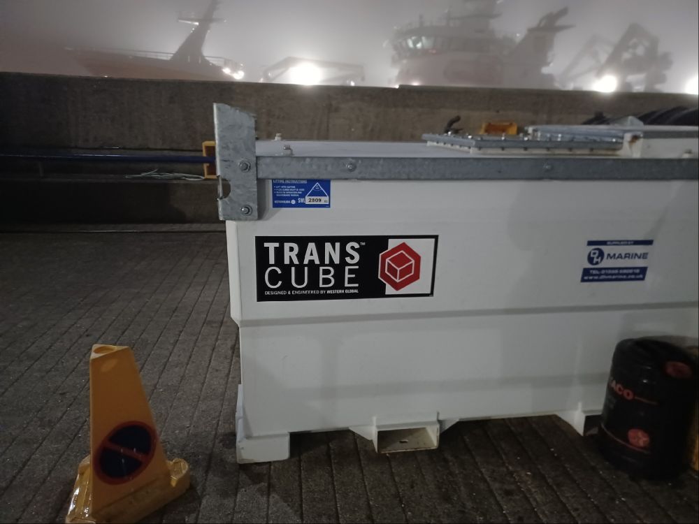 a white transport container on a foggy harbour dock. the container is labelled "TRANS CUBE"