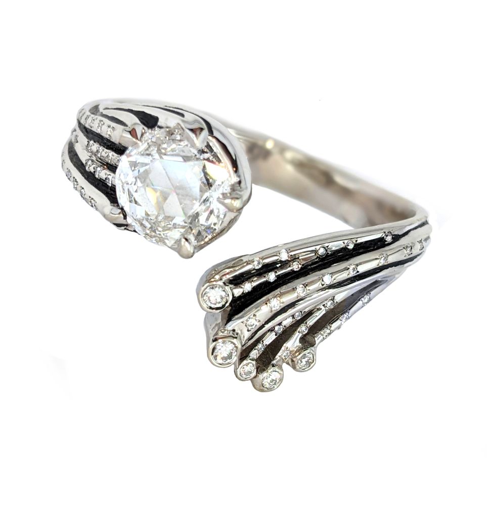 White gold ring in the shape of an artistic comet, with the head represented by a brilliant diamond. The shape of the comet's tail is brought out by small diamonds and thin black enamel, showing the black of the Void through which the comet travels.