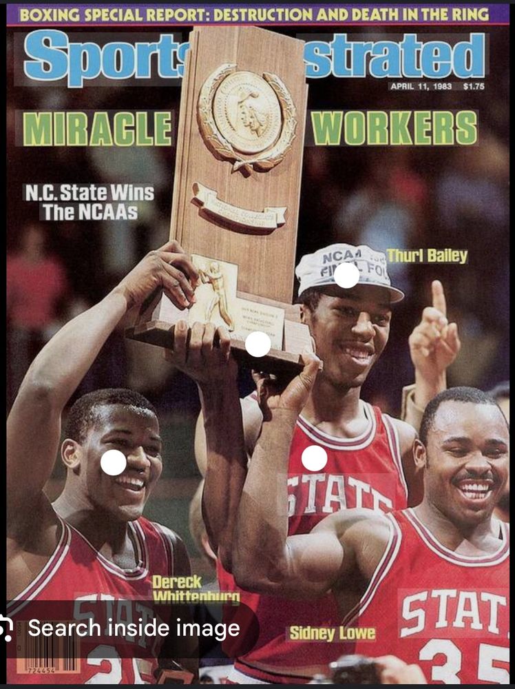Three basketball players in red jerseys holding a championship trophy aloft.