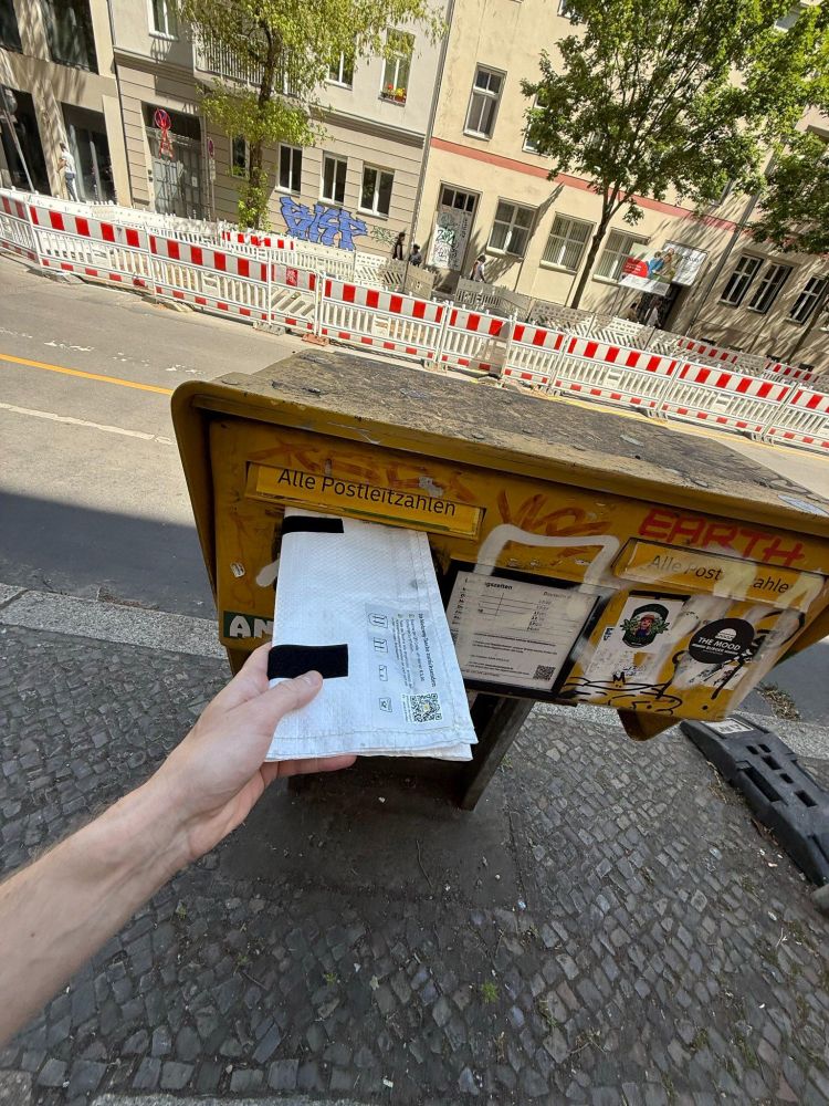 Eine gefaltete Ravioli Mehrweg-Tasche wird in einen Briefkasten der Deutschen Post eingeworfen.