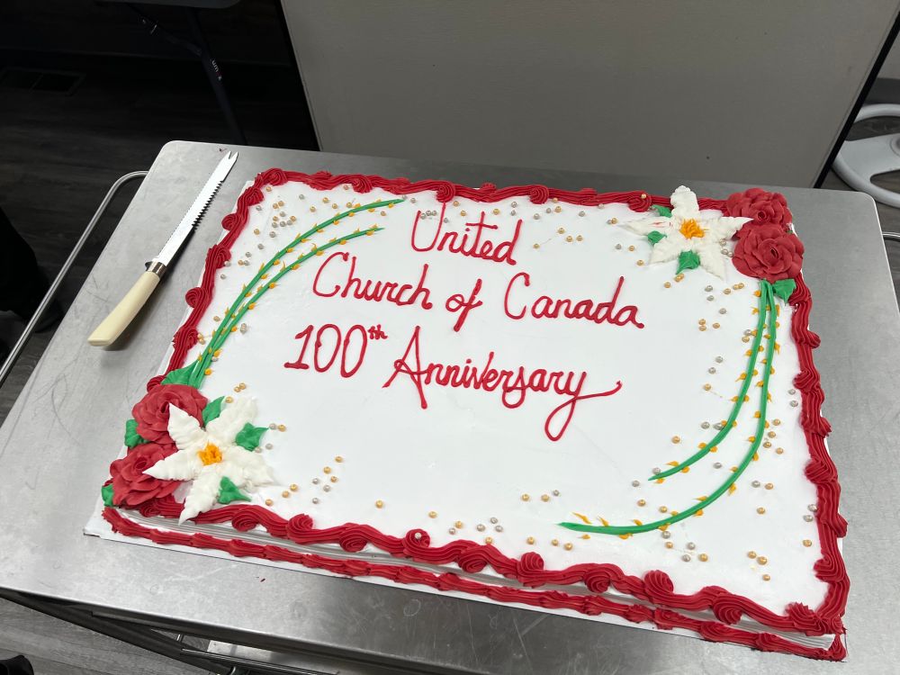 A cake that reads “United Church of Canada 100th Anniversary”