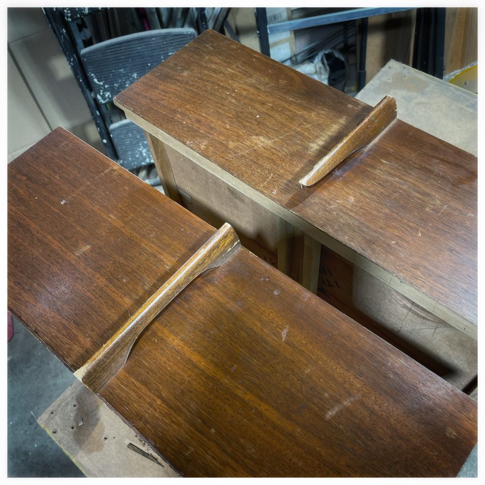 Beaten up drawers to a mid century modern dresser, featuring elegant wooden handles