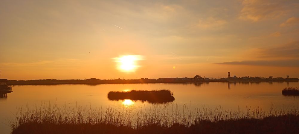 A picture of the sunset from an earlier period of time, with it being partially reflected by the waters