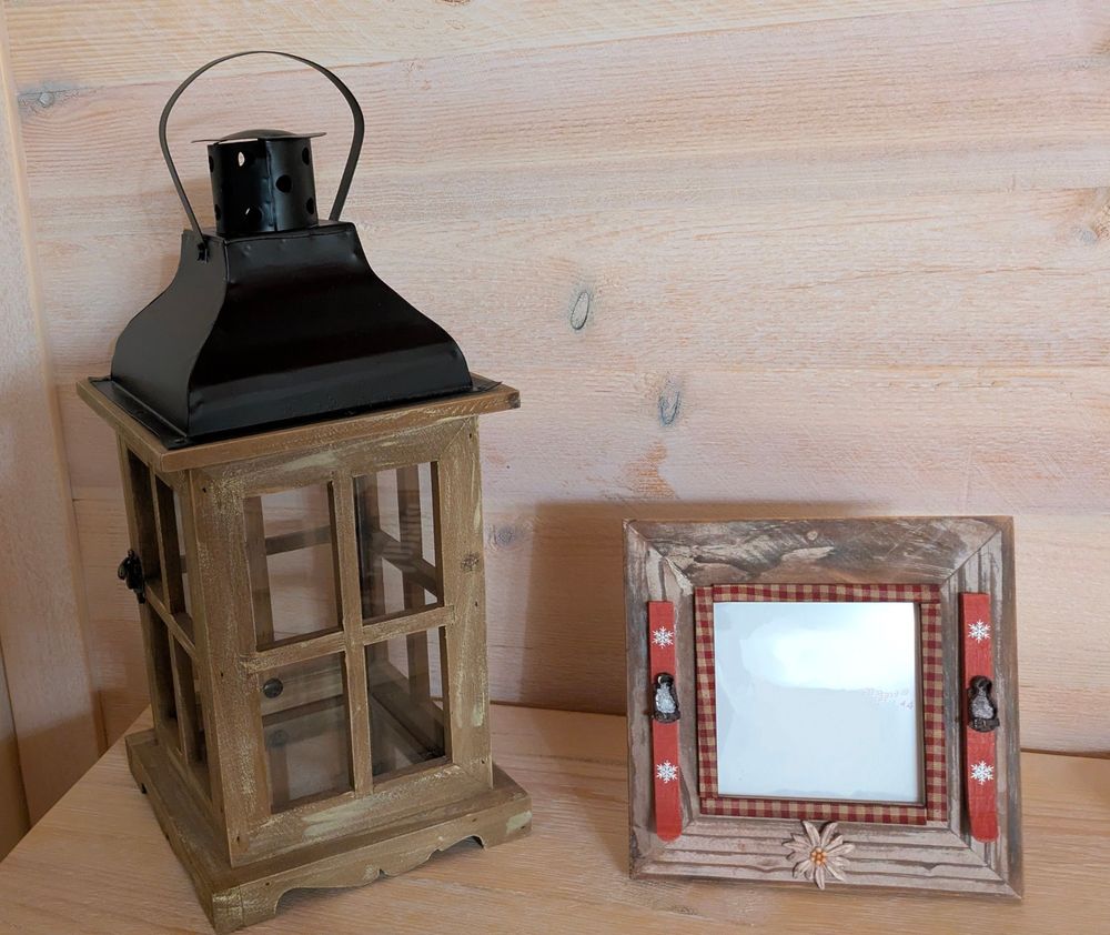 A lantern (on the left) and a wooden frame for photos (on the right) on a table 