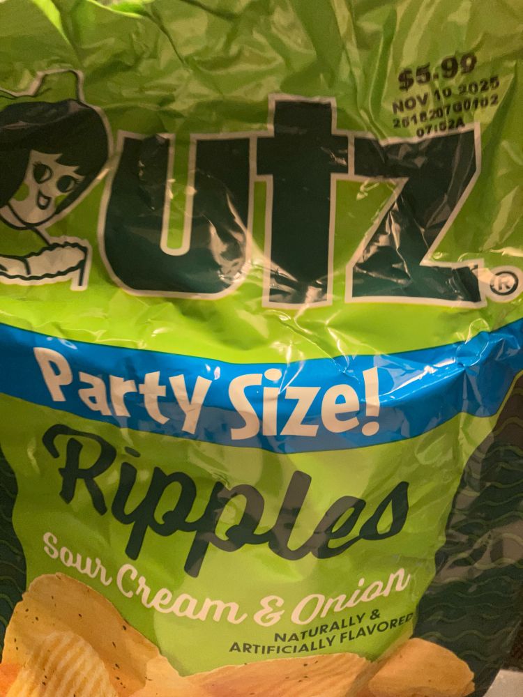 A crumpled bag of Utz Party Sized sour cream and onion chips 