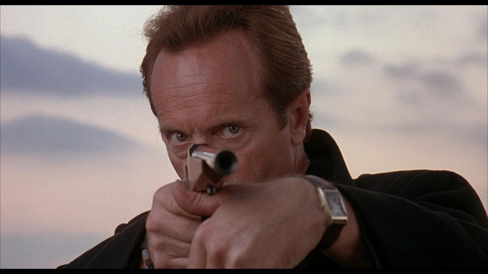 Actor Lance Henriksen, pointing a gun in the viewer’s direction.