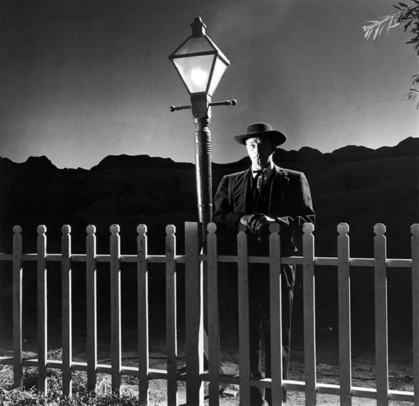 Robert Mitchum at the gate in an artificial landscape in THE NIGHT OF THE HUNTER (Laughton, 1955)