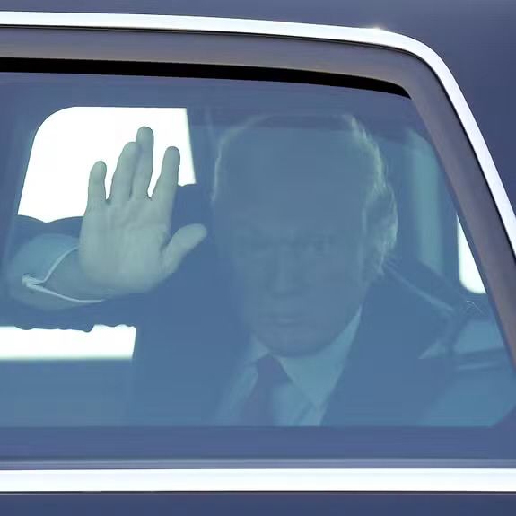 Trump waving in the back seat of a car 