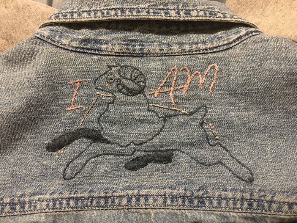 embroidery of a ram overlaying the aries constellation, with the words “i am” 
