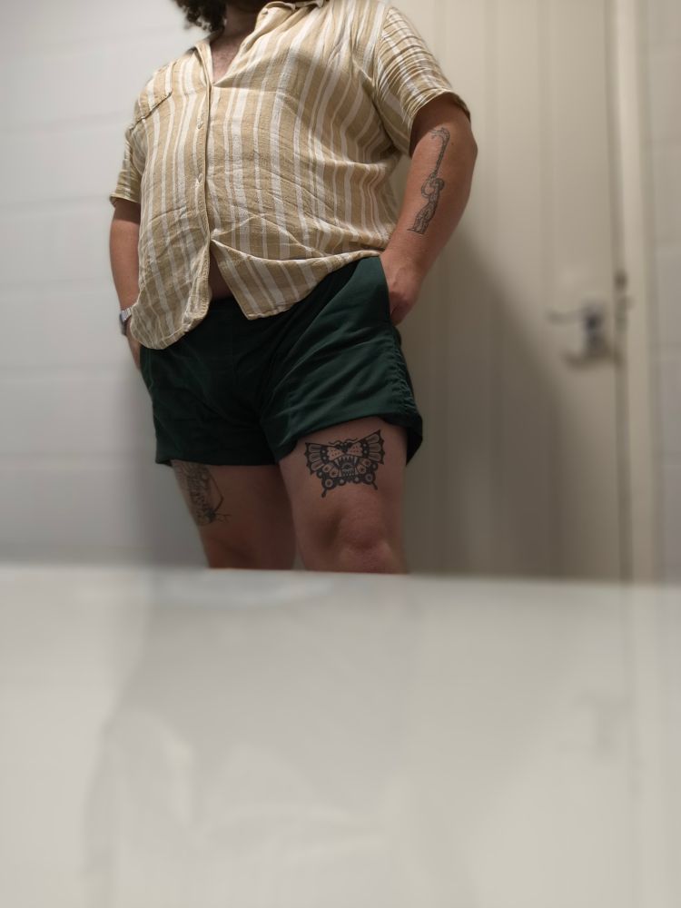 Me in green shorts and a yellow and white striped shirt, cut off at the head. You can see my moth tattoo on my right thigh