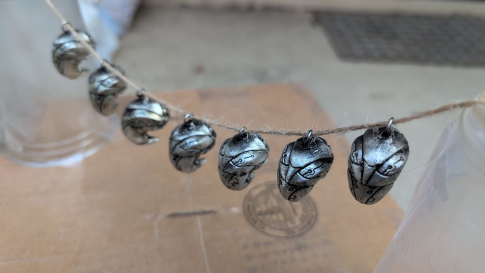 photo of pewter pendants of biomech grubs (back)