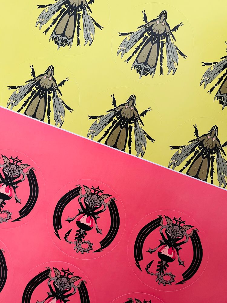 Photo of two sheets of circular sticker designs, one depicting a biomechanical insect and the other a skeletal hourglass