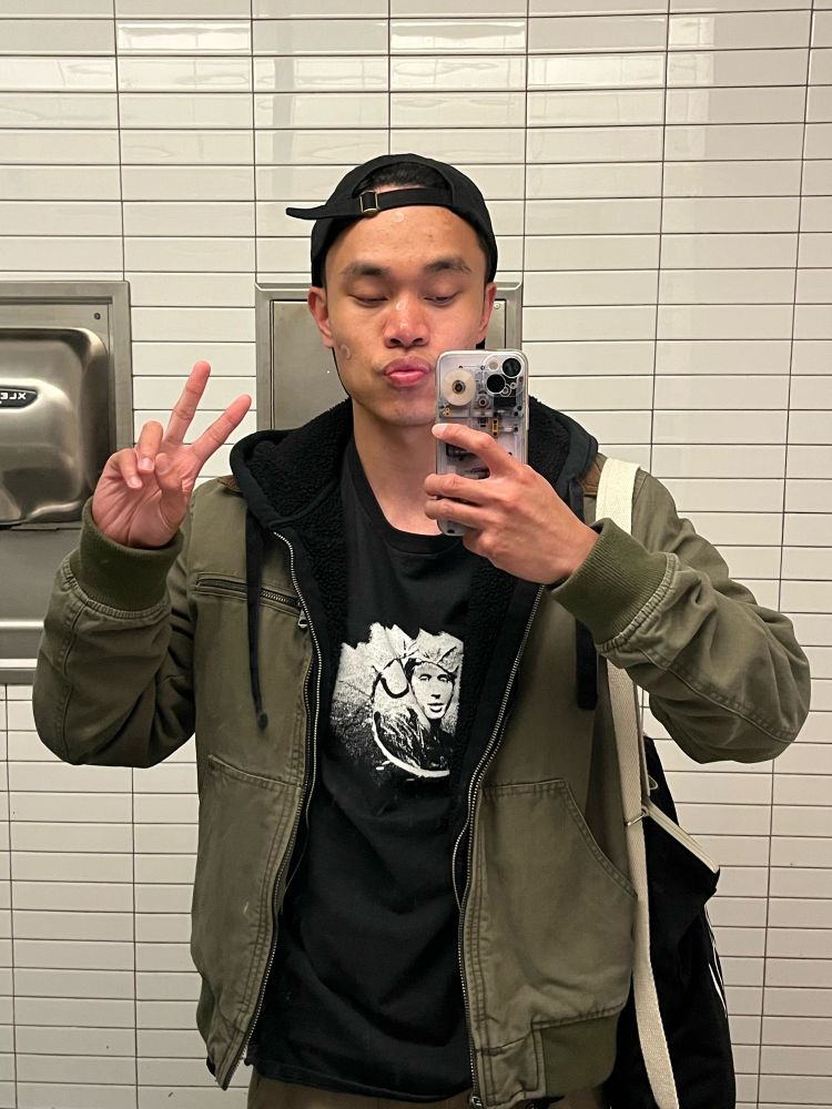 Brandon, throwing a peace sign in the art gallery bathroom while decked out in a Troye Sivan gloryhole tee w/ two pimple patches on his face