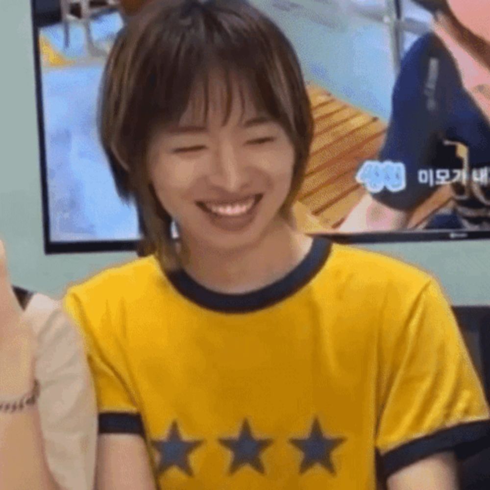 a young woman wearing a yellow shirt with three stars on it is smiling .