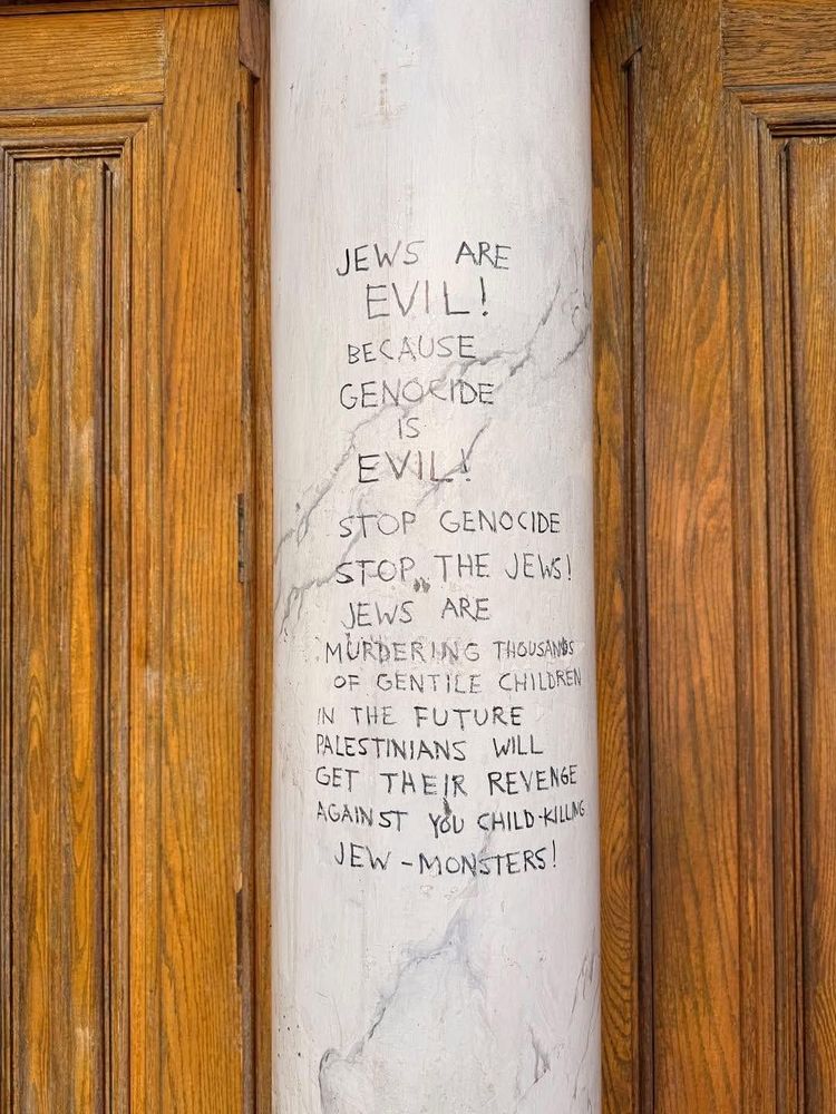 A stone marble post sits between two oak doors. On the marble in permanent marker reads the following: 'JEWS ARE EVIL! BECAUSE GENOCIDE IS EVIL! STOP GENOCIDE STOP THE JEWS JEWS ARE MURDERING THOUSANDS OF GENTILE CHILDREN IN THE FUTURE PALESTINIANS WILL GET THEIR REVENGE AGAINST YOU CHILD-KILLING JEW-MONSTERS!'