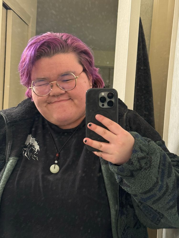 A mirror selfie of me. I have purple hair and a big cozy sherpa jacket on