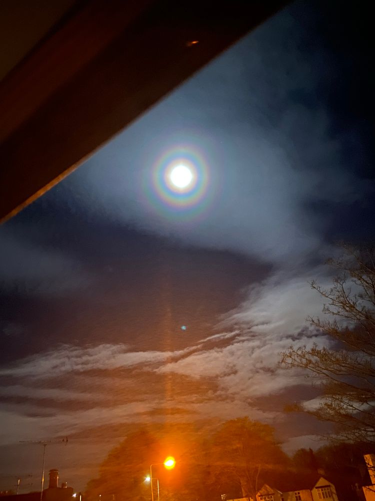 A photograph of the moon with a rainbow-like halo surrounding it in the sky. 