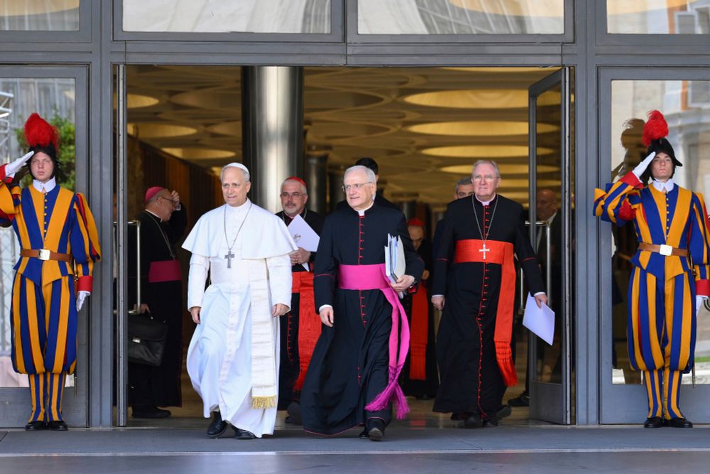 Pope Leo XIV, left, is flanked by Monsignor Leonardo Sapienza, second from left, after his meeting with the College of Cardinals in the New Synod Hall at the Vatican, Saturday, May 10, 2025. (Vatican Media via AP)