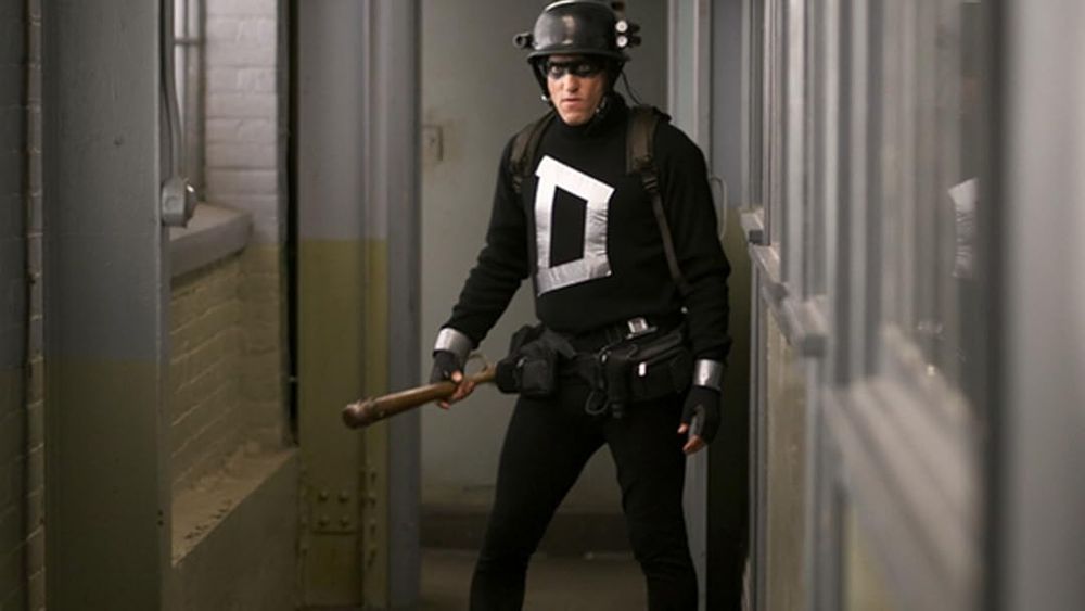 Woody Harrilson as Defendor in the movie with the same name. He's wearing an all black costume with the letter D on his chest made with gray duct tape