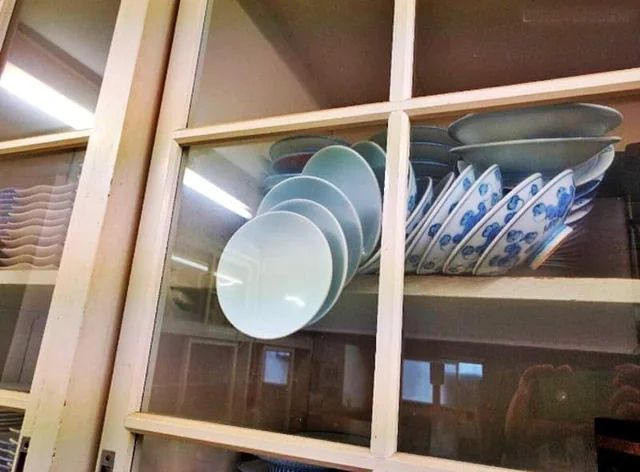 Assiettes en déséquilibre maintenues dans une vitrine par la porte 
