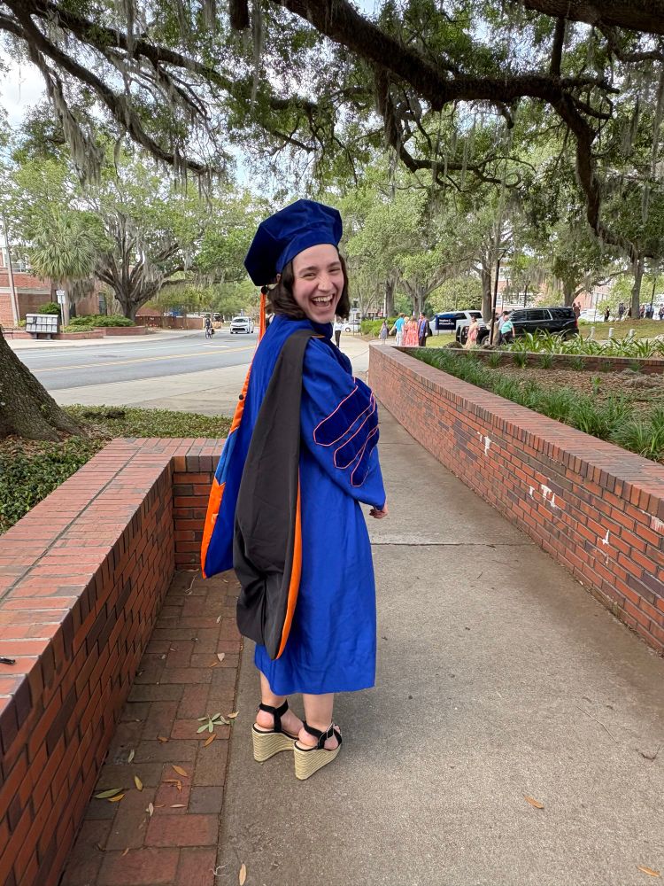 Laughing in orange and blue doctoral regalia after University of Florida doctoral commencement ceremony. 