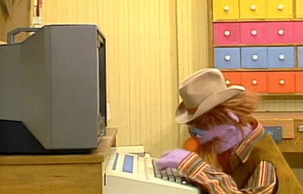 a muppet wearing a cowboy hat is typing on a computer keyboard