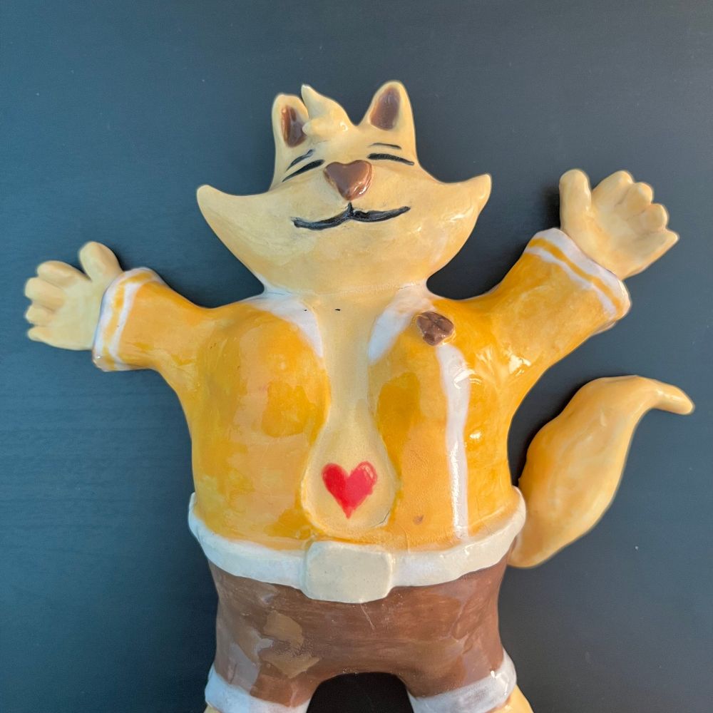 Closeup of ceramic model of chubby anthro cat laying down sleeping, has a heart belly button, calm face expression can be seen