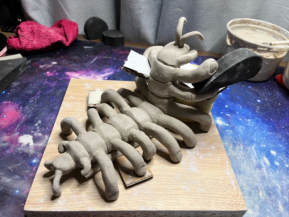 Centipede made of clay, instead of legs and other features, there are human fingers