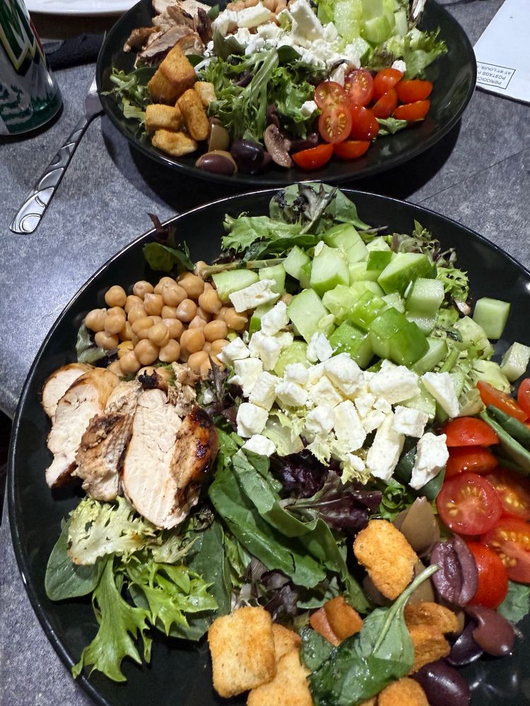 Homemade Greek salad with mixed greens, chickpeas, chopped cucumber, sliced cherry tomatoes, Kalamata olives, feta cheese and grilled chicken