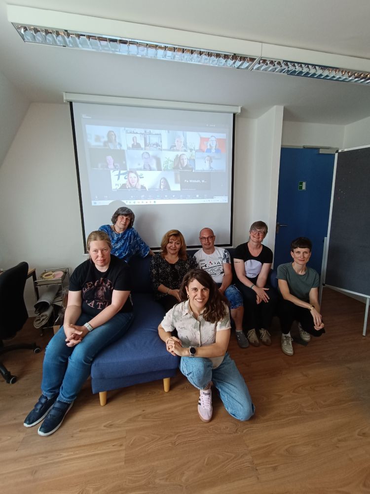 Foto des Suse-Beirats während eines Treffens – Personen sitzen gemeinsam vor einer digitalen Raum-Wand mit weiteren Teilnehmenden.