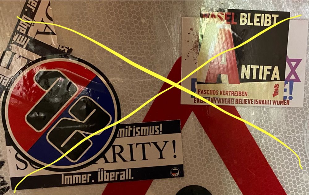 Ein Aufkleber gegen Antisemitismus überklebt von einem Aufkleber JUSO Basel und ein weiterer überklebt von einem Aufkleber der Muttenzerkurve Basel.

Aufkleber der JUSO Basel: Basel bleibt Antifa. Faschos vertreiben. Logo der JUSO Schweiz

Aufkleber gegen Antisemitismus von Juso überklebt: Rape is not ressistance. Ever! Anywehre! Believe Israeli Women, dazu ein Davidsstern.

Aufkleber der Muttenzerkurve Basel: Ein runder Aufkleber der in der mitte rot/blau geteilt ist. Darüber ein grosses "12"
Aufkleber der von dem Muttenzerkurve Aufkleber überklebt ist: Ein länglich-breiter Aufkleber, in der Mitte steht gross "SOLIDARITY!" im "O" ist ein Davidsstern. Obendrüber steht "Gegen jeden Antisemitismus!", zuunterst "immer, überall" und ein Antifa-Logo.