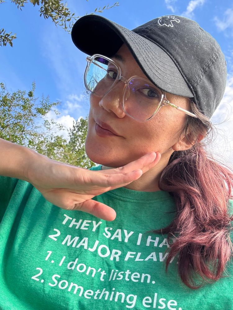 photo of joa a half korean half irish person wearing a black baseball hat with a lil ghost embroidered on it, clear glasses, and a green shirt that has white text reading THEY SAY I HAVE 2 MAJOR FLAWS: 1. I don’t listen. 2. Something else.

my hair is muted reddish and dark brown like if the dr pepper logo was a hair color? and i’m holding my hand up to my chin as if to say hey! hello! hi! it me! 
