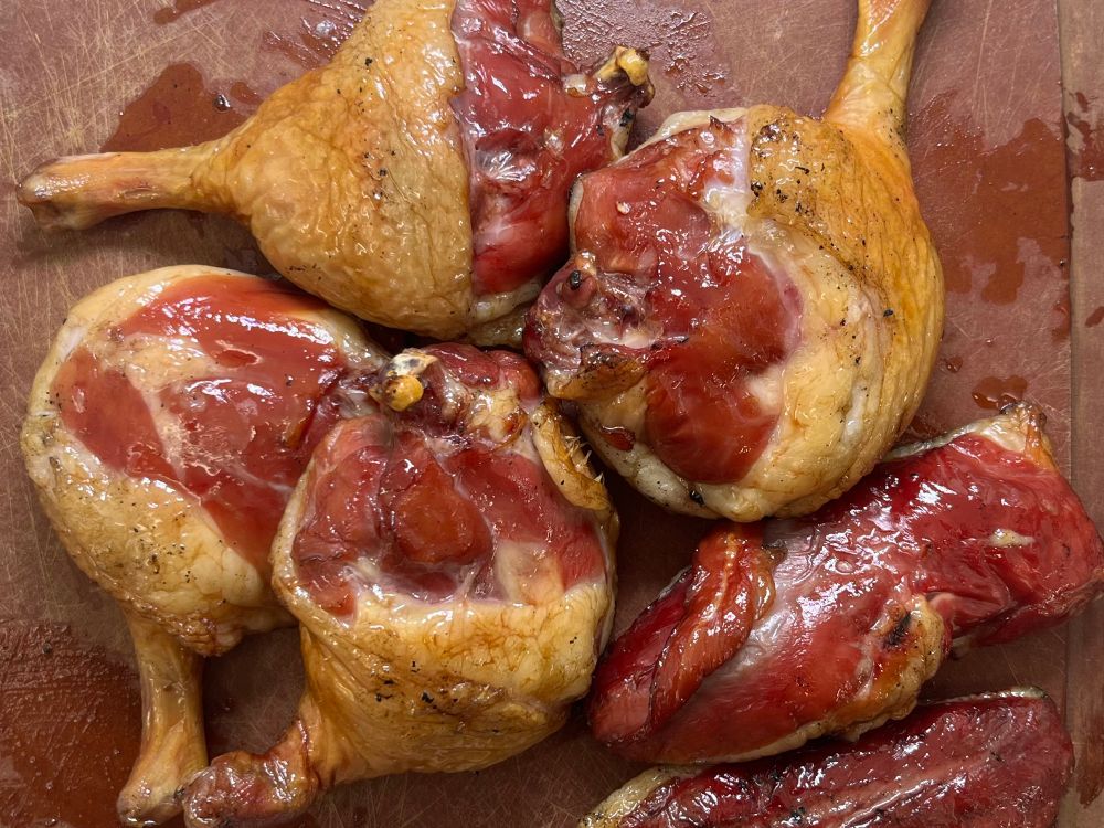 Parted and smoked duck legs and breast displayed off the grill in a mess.