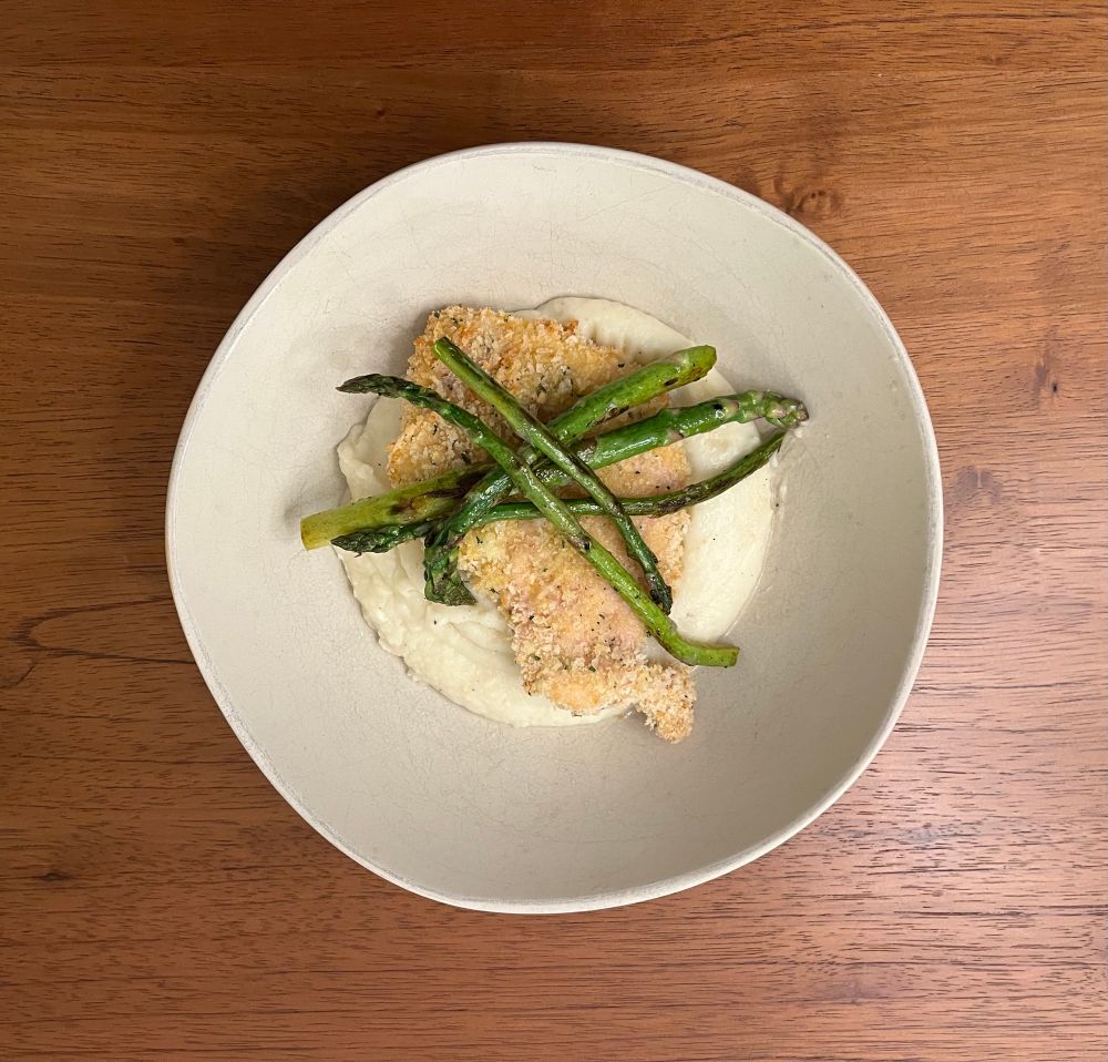 Panko crusted chicken plated over whipped turnip and parsnips, garnished with asparagus spears. 