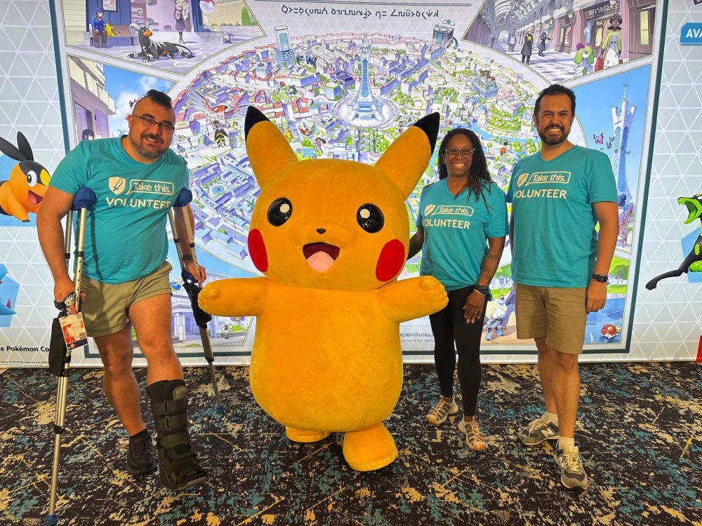 Three Take This volunteers pose next to Pikachu