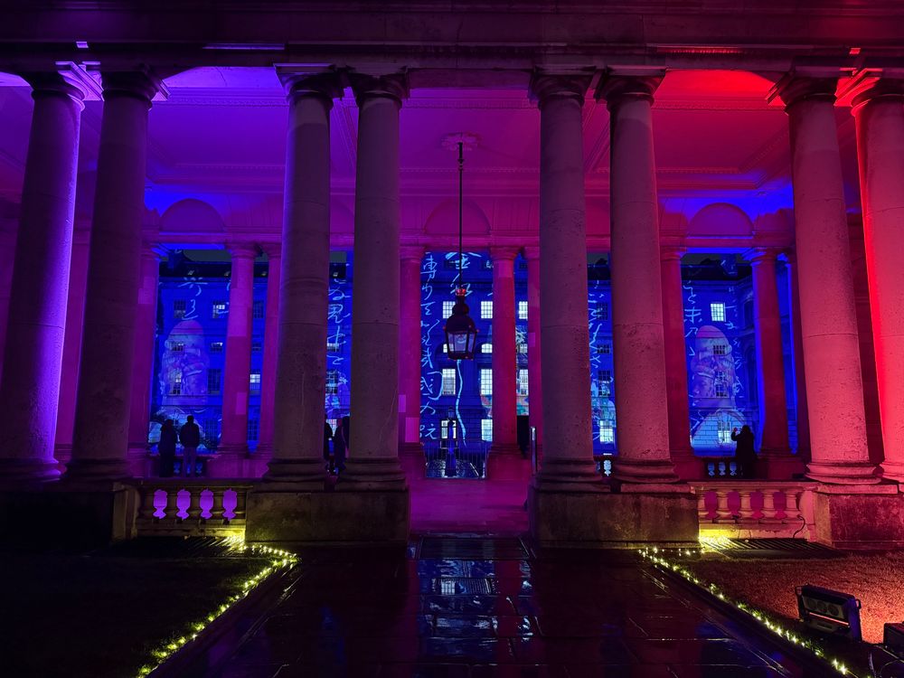 Projections on a 4-storey high wall seen through multiple vividly-lit columns