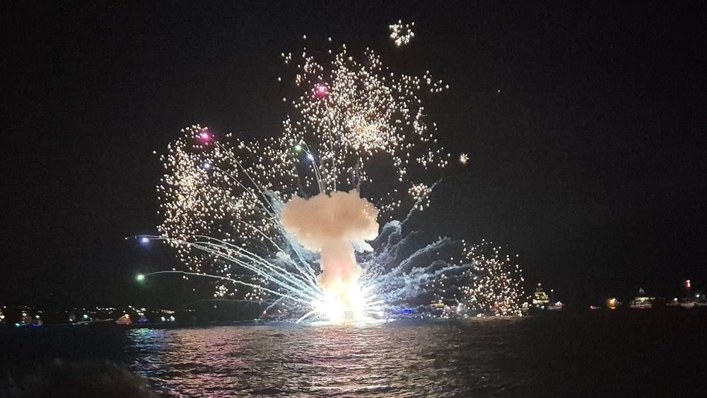 Fireworks across the sea. This is the ceremonial burning of a boat as part of the festival. 