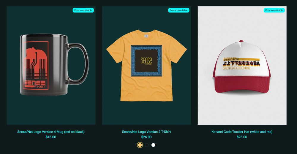 Screenshot of the store showing three articles:
A black mug with a red design for the fictional "Sense/Net" corporation
A yellow t-shirt with a different logo for Sense/Net
A trucker cap in red and white with the Konami Code in Black, Red, and yellow Japanese glyphs