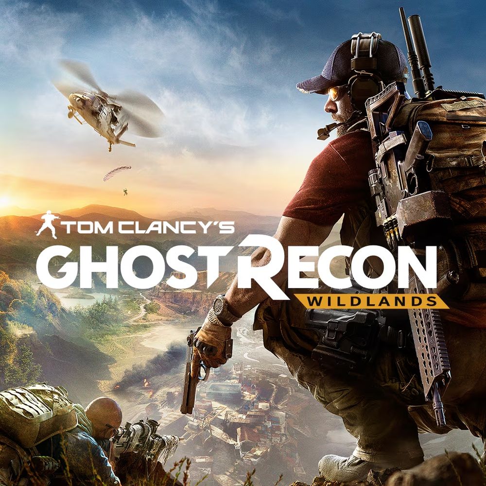 Tom Clancy’s Ghost Recon Wildlands.” A heavily armed soldier kneels on a cliff overlooking a desert canyon battle—helicopter and parachutist in the sky, smoke and teammates below—with the bold white title across the center.